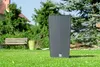 A dark gray planter sits on a green lawn in front of trees and a house. Anteprima dell’immagine prodotto