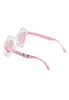 A pair of children's sunglasses with a flower-shaped frame and pink lenses. Produktbild-Vorschau