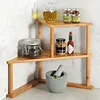 A corner shelf unit made of bamboo, holding various kitchen items like jars of spices, oil, mustard, and hot sauce, along with a mortar and pestle. Produktbild-Vorschau