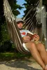 A man is reading a book while sitting in a hammock. Produktbild-Vorschau