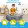 A young boy is playing with building blocks while sitting on a folded mattress in a playroom. Decorative elements like clouds and stars are on the wall, and storage units are in the background. Produktbild-Vorschau
