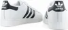 Two views of a pair of white Adidas Superstar sneakers with black accents. Voir les images du produit