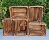 Several wooden crates are arranged on a gray surface in front of a green hedge. Náhled obrázku produktu