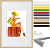 A framed picture of a woman sitting on a suitcase, with a selection of frame colors and dimensions shown on the right. Produktbild-Vorschau