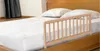 A wooden bed rail is attached to the side of a bed with white bedding and pillows. Voir les images du produit