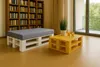 A living room with a bookshelf, a pallet bench with a gray cushion, and a yellow pallet coffee table with drinks and a plant. Anteprima dell’immagine prodotto