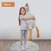 A young girl is hugging a large stuffed goose toy. Náhľad obrázku produktu