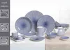 A collection of blue and white patterned tableware, including plates, bowls, and a teapot, arranged on a table. Produktbild-Vorschau