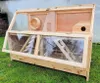 A wooden animal cage with clear plastic windows, placed on grass. Produktbild-Vorschau