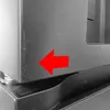 A close-up of the bottom corner of a stainless steel appliance, with a red arrow pointing to a scuff mark. Produktbild-Vorschau
