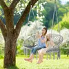 Two young girls are sitting in a hanging chair in a garden. Náhľad obrázku produktu