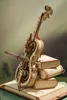 A wooden mechanical cello model with gears, resting on a stack of wooden books. Voir les images du produit
