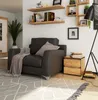 A living room scene with a dark gray armchair, a wooden nightstand, and shelves with books and decor. Produktbild-Vorschau
