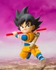 A stylized action figure of Son Goku from Dragon Ball, posed dynamically with a red staff and a bamboo quiver on his back, against a vibrant pink and brown sky. Produktbild-Vorschau