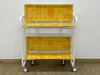 A two-tiered serving cart with a white metal frame and yellow patterned trays. Anteprima dell’immagine prodotto