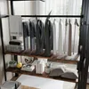 A closet or wardrobe area with clothes hanging on a rack and items on shelves. Podgląd zdjęcia produktu