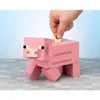 A hand is placing a coin into a pink Minecraft pig piggy bank. Podgląd zdjęcia produktu