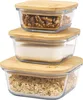 Three glass storage containers with bamboo lids are stacked on top of each other. The top container holds walnuts, the middle container holds sugar, and the bottom container holds oats. Produktbild-Vorschau