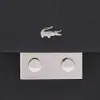 A close-up of a black bag with a silver crocodile logo and a silver clasp. Anteprima dell’immagine prodotto