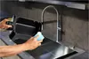 A person is cleaning an air fryer basket in a modern kitchen sink. Voir les images du produit