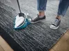 A person is using a steam cleaner on a rug. Anteprima dell’immagine prodotto
