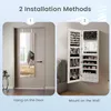 The image shows two installation methods for a jewelry cabinet: hanging on a door and mounting on a wall. The cabinet is white and filled with jewelry. Náhľad obrázku produktu