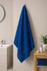 A blue towel hanging on a hook in a bathroom. Produktbild-Vorschau