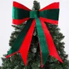 A decorative bow made of red and green velvet ribbon, placed on top of a Christmas tree. Produktbild-Vorschau