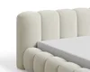 Close-up view of a beige upholstered bed frame with a mattress. Voir les images du produit