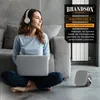 A woman is sitting on the floor with a laptop and headphones, next to a heater and a small fan. Anteprima dell’immagine prodotto