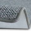 A close-up view of a gray carpet, showing its texture and edge binding. Produktbild-Vorschau