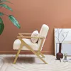 A cozy living room scene featuring a fluffy white armchair, a large potted plant, and decorative items. Produktbild-Vorschau