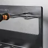 A close-up shot of a screwdriver being used to attach a metal spice rack to a wall. Produktbild-Vorschau