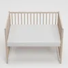 A baby crib with a white mattress on a white background. Produktbild-Vorschau