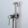 A chrome bidet sprayer and faucet mounted on a light gray wall. Podgląd zdjęcia produktu