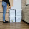 A person is shown sorting trash into a stack of white bins. Náhled obrázku produktu
