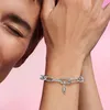 A close-up shot of a person's arm wearing a silver charm bracelet with a feather-shaped charm. Anteprima dell’immagine prodotto