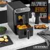 A black dual-chamber air fryer is shown on a kitchen counter, with food items like fries, chicken nuggets, and potato wedges arranged around it. Text overlays highlight its features. Produktbild-Vorschau
