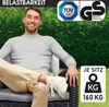 A man is sitting on a polyrattan garden chair, with a green hedge in the background. There are certification logos and text indicating load capacity. Produktbild-Vorschau
