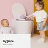 Two babies are near a toilet with a pink potty seat. One baby is reaching for a toy on the seat. Produktbild-Vorschau