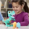 A young girl is playing with a toy dinosaur and Play-Doh eggs. Náhled obrázku produktu