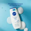 A bottle of Nivea Creme Soft & Almond shower gel is shown on a light blue background with foam and water droplets. Produktbild-Vorschau