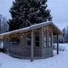 A wooden cabin decorated with warm white LED string lights in a snowy environment. Podgląd zdjęcia produktu