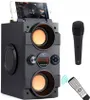 A black portable Bluetooth speaker with a smartphone docked on top, a microphone to the right, and a remote control at the bottom right. Podgląd zdjęcia produktu