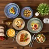 A top-down view of a table setting with multiple plates of food and decorative elements. Produktbild-Vorschau