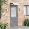 A door awning is installed above a gray door on a brick wall. Náhled obrázku produktu