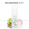 A bottle of Wella Nutricurls Curlixir Balm is displayed with decorative elements like a slice of lime, leaves, cinnamon sticks, and a pink flower. Voir les images du produit