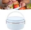 A person is packing a lunchbox with a sandwich, apple, and tomato. Below is a picture of the lunchbox itself. Produktbild-Vorschau