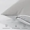 A close-up view of a light gray pillowcase with a zipper, showing care instructions and feature icons at the bottom. Voir les images du produit