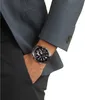 A man wearing a suit jacket and trousers, with his hand in his pocket, showing off a wristwatch. Voir les images du produit